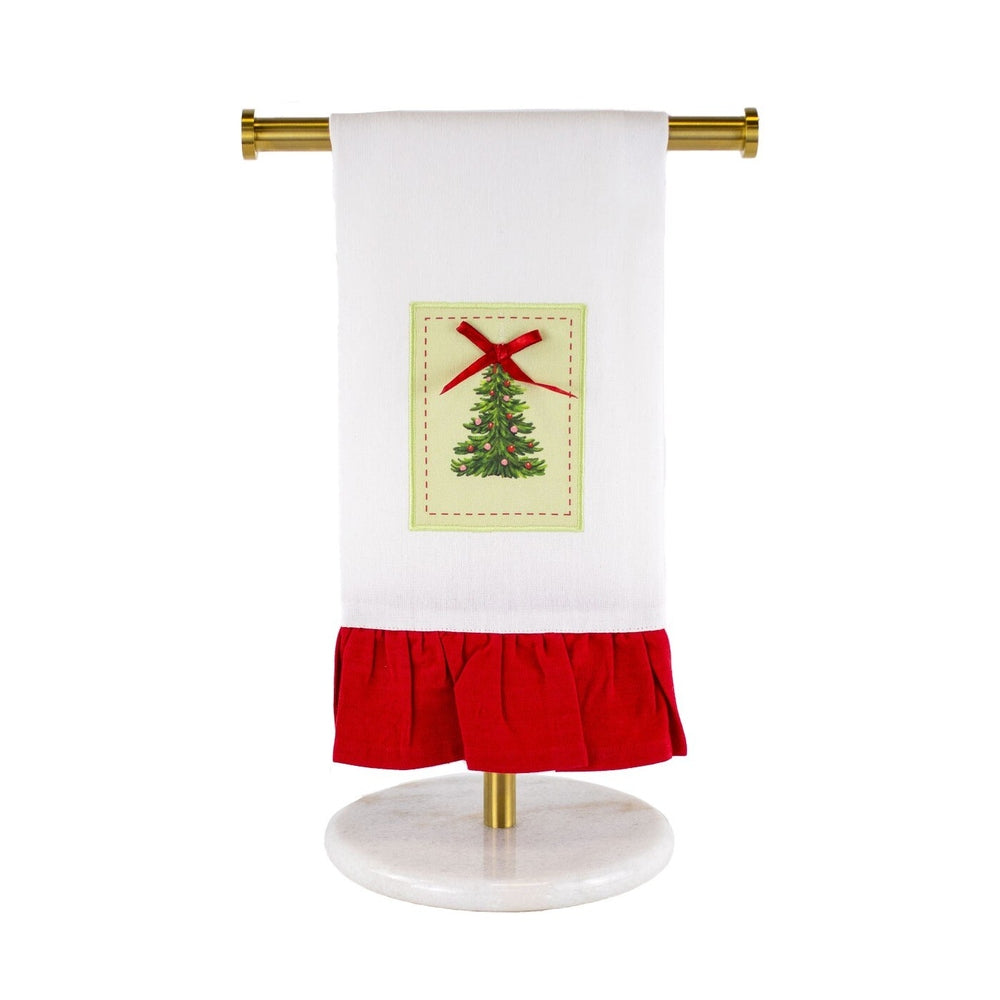 White hand towel with a Christmas tree patch and red ruffled hem hanging on a gold stand