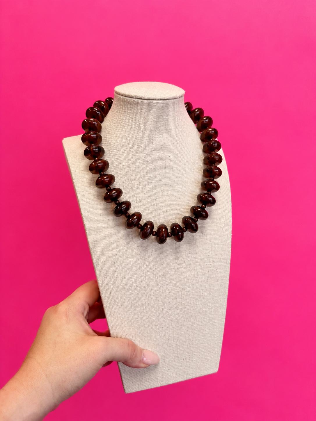 Brown bauble bead necklace on a display bust against pink