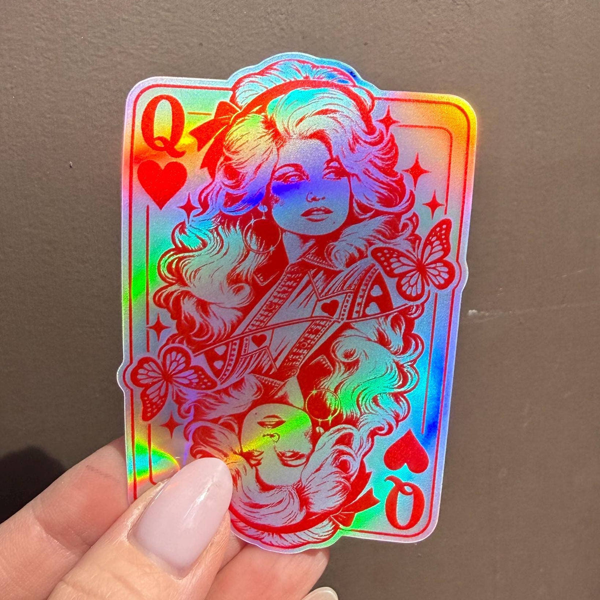 Hand holding a holographic queen of hearts playing card sticker