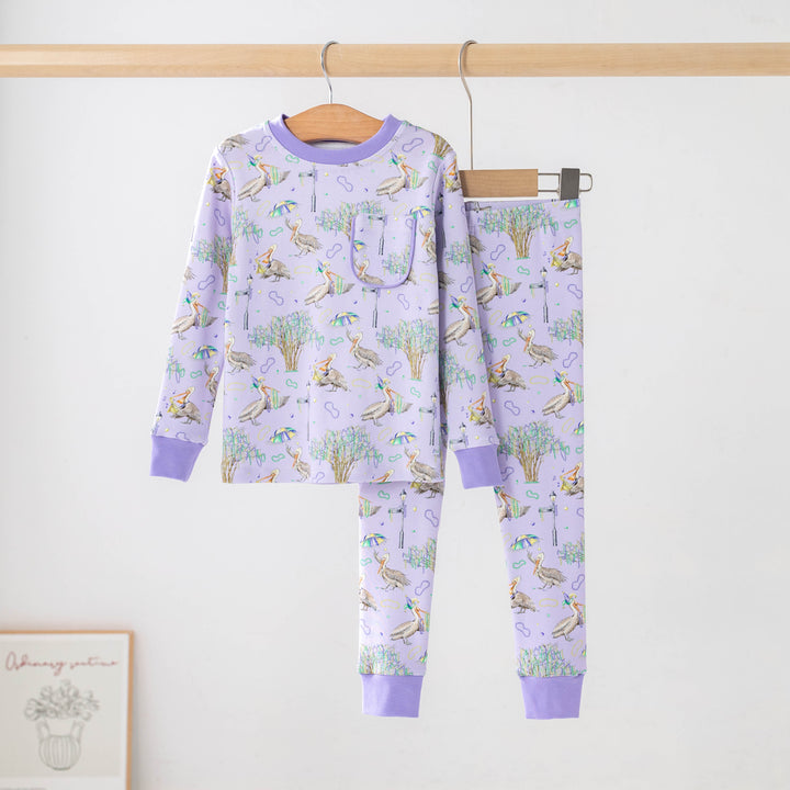 Lavender two-piece pajama set with a print of pelicans, oak trees, parasols and Mardi Gras beads