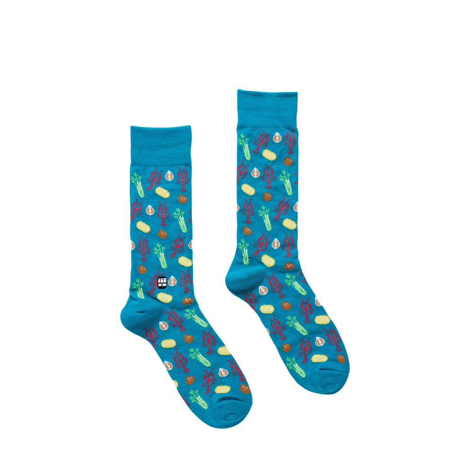 Pair of teal crew socks with a repeating pattern of crawfish corn celery and garlic