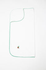 White blanket with green trim and embroidered design on a white background