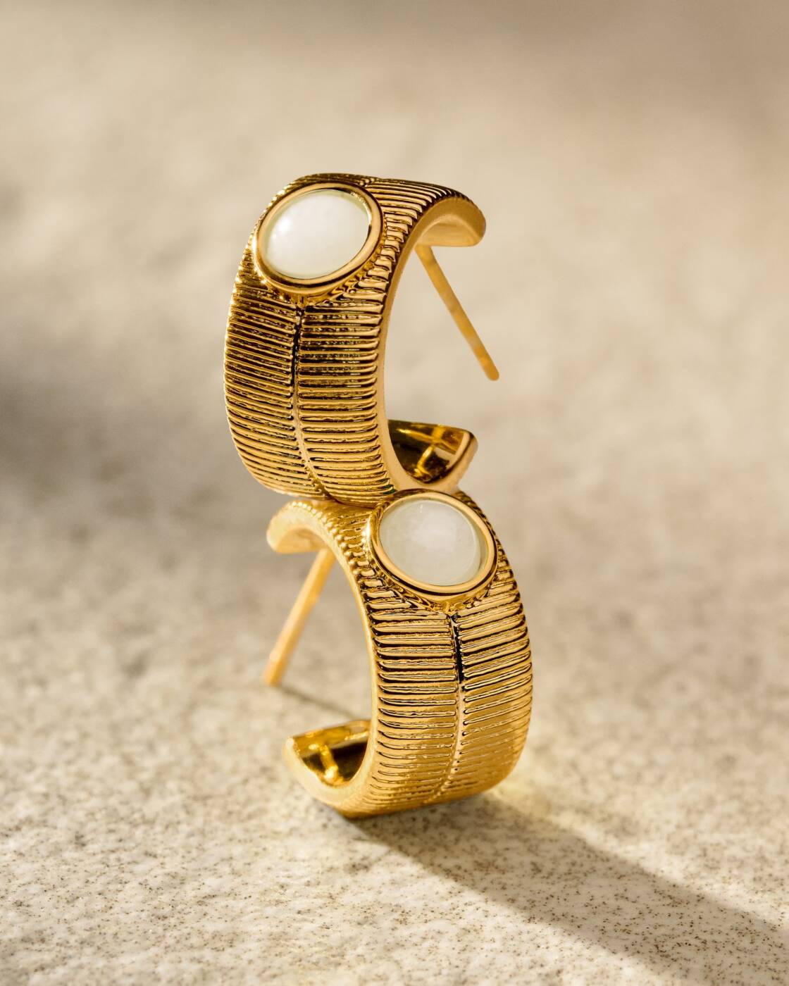 Gold hoop earrings with textured finish and white stone inlay