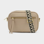 Beige camera bag shaped purse with a patterned strap on a light gray background