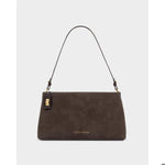 Vegan suede handbag by Katie Loxton featuring a chocolate brown rectangular silhouette with an adjustable thin strap and gold-tone metal hardware against a neutral grey background