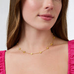 Gold chain necklace with small circular charms worn by a woman