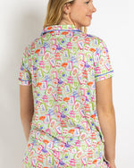 Woman wearing a light green pajama top with a colorful mahjong tile print