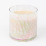 A multicolored candle with an iridescent tortoise finish, containing a white wax, housed in a clear glass vessel.
