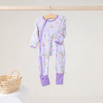 Lavender zip footie with a print of pelicans, oak trees, parasols and Mardi Gras beads