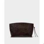 Vegan leather clutch by Katie Loxton featuring a dark espresso brown high-shine crinkle finish, gold logo lettering, and a side knotted tassel with a gold charm against a neutral background
