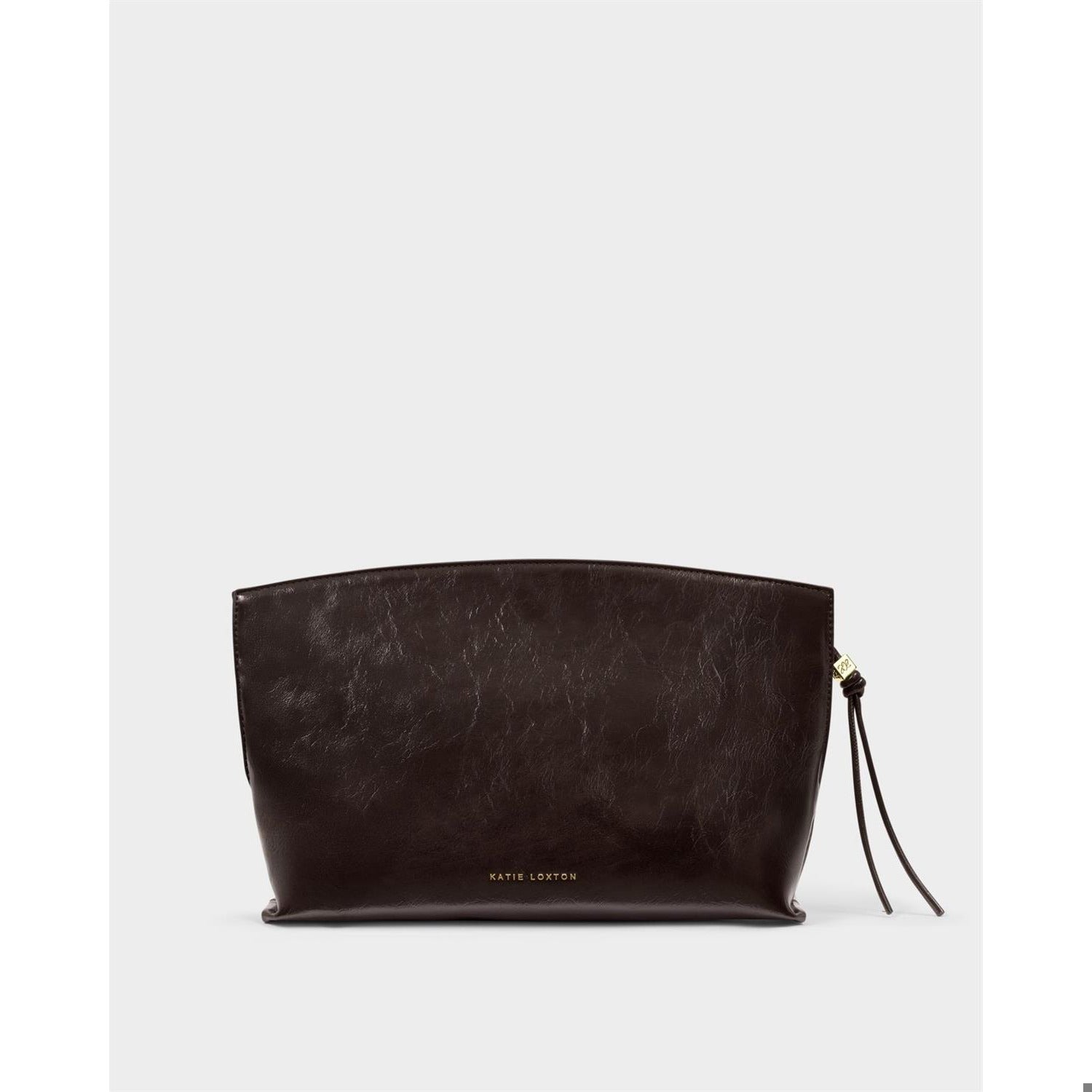 Vegan leather clutch by Katie Loxton featuring a dark espresso brown high-shine crinkle finish, gold logo lettering, and a side knotted tassel with a gold charm against a neutral background