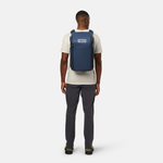 Person wearing a blue YETI backpack on a white background