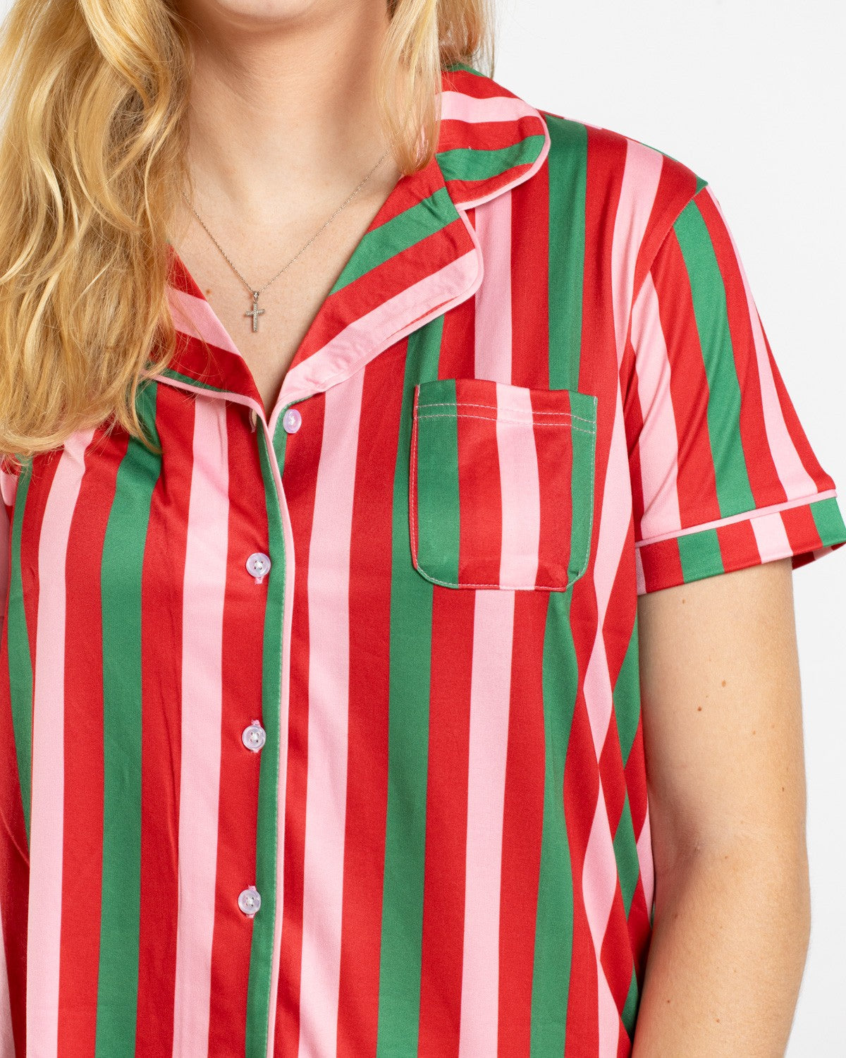 Person wearing a short sleeve button down pajama top with red green and pink vertical stripes and a chest pocket