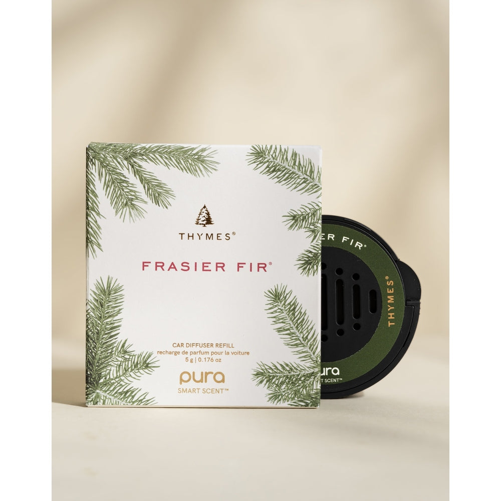 Studio photograph of Thymes Frasier Fir Pura Smart Scent car diffuser refill featuring the iconic brand tree logo, green fir needle illustrations, and a black circular scent pod on a neutral beige background
