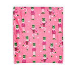 Pink blanket with repeating nutcracker soldier pattern and white snowflakes