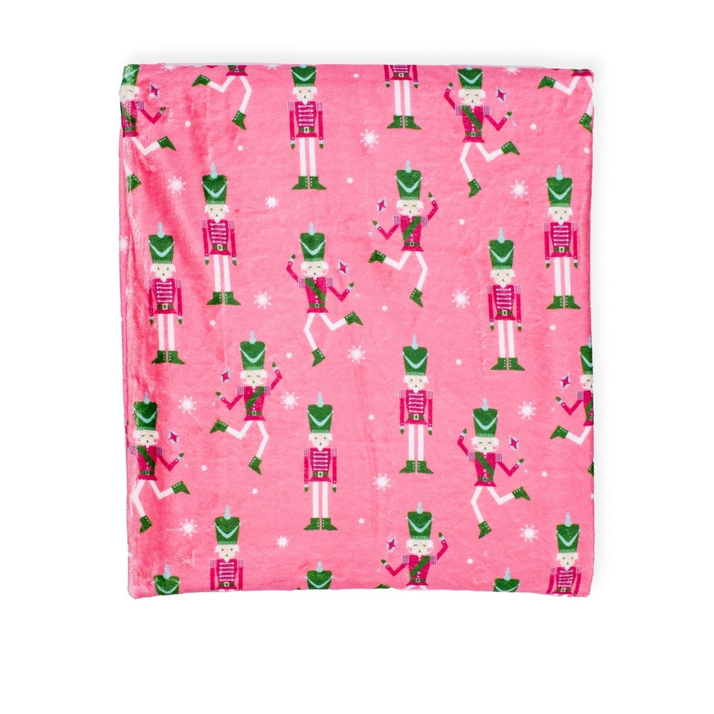 Pink blanket with repeating nutcracker soldier pattern and white snowflakes
