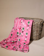 Pink blanket with nutcracker pattern draped over a wicker basket