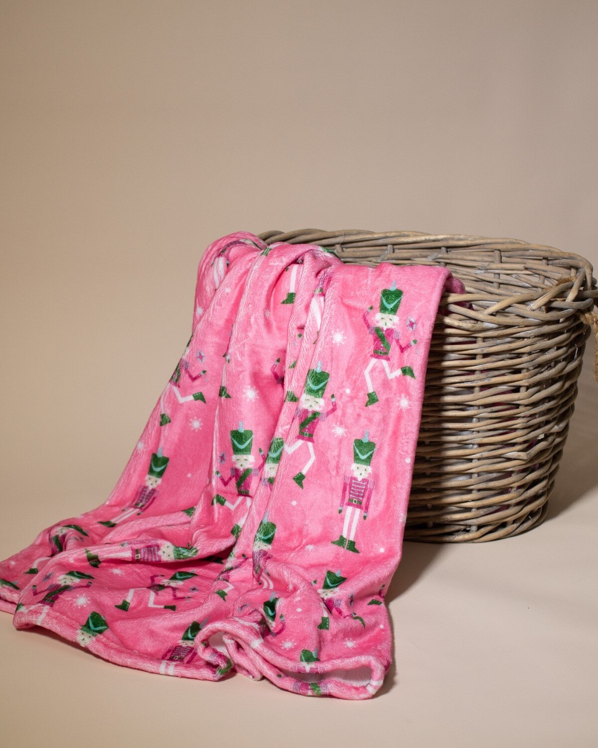 Pink blanket with nutcracker pattern draped over a wicker basket