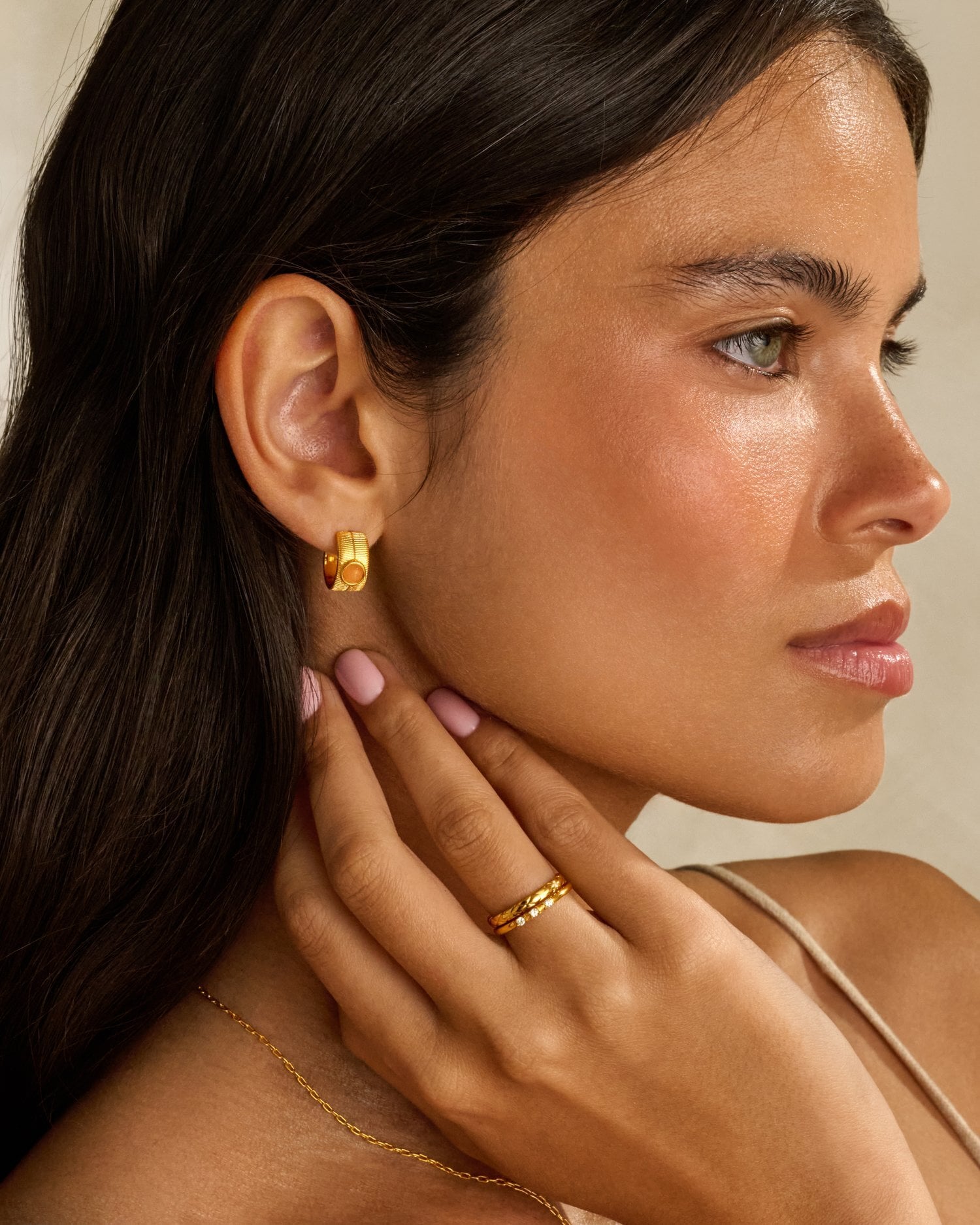 Woman wearing gold hoop earring and stacked gold rings