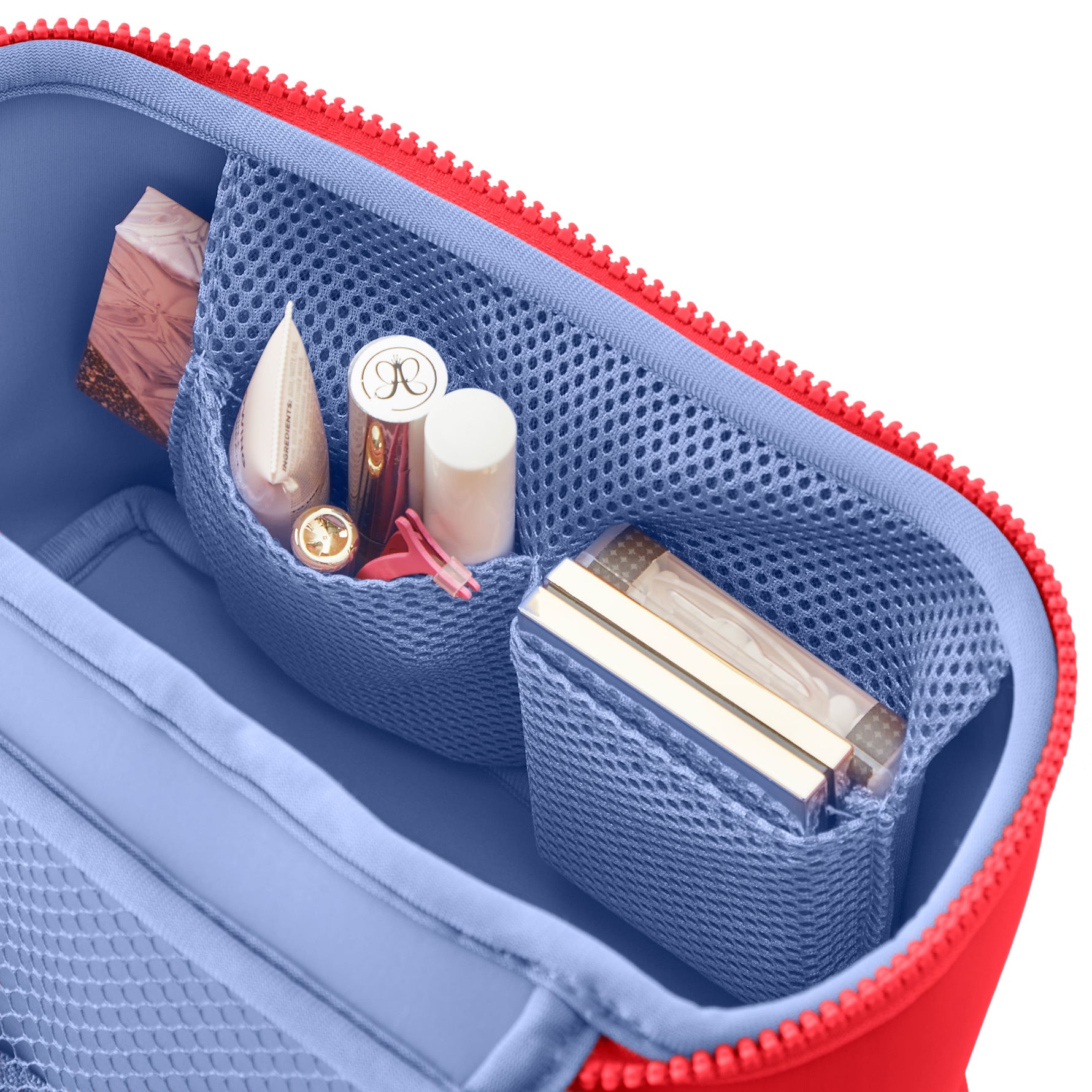Blue and red cosmetic bag with makeup items inside on a white background