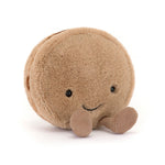 Tan plush macaron with a smiling face and brown corduroy feet, angled view