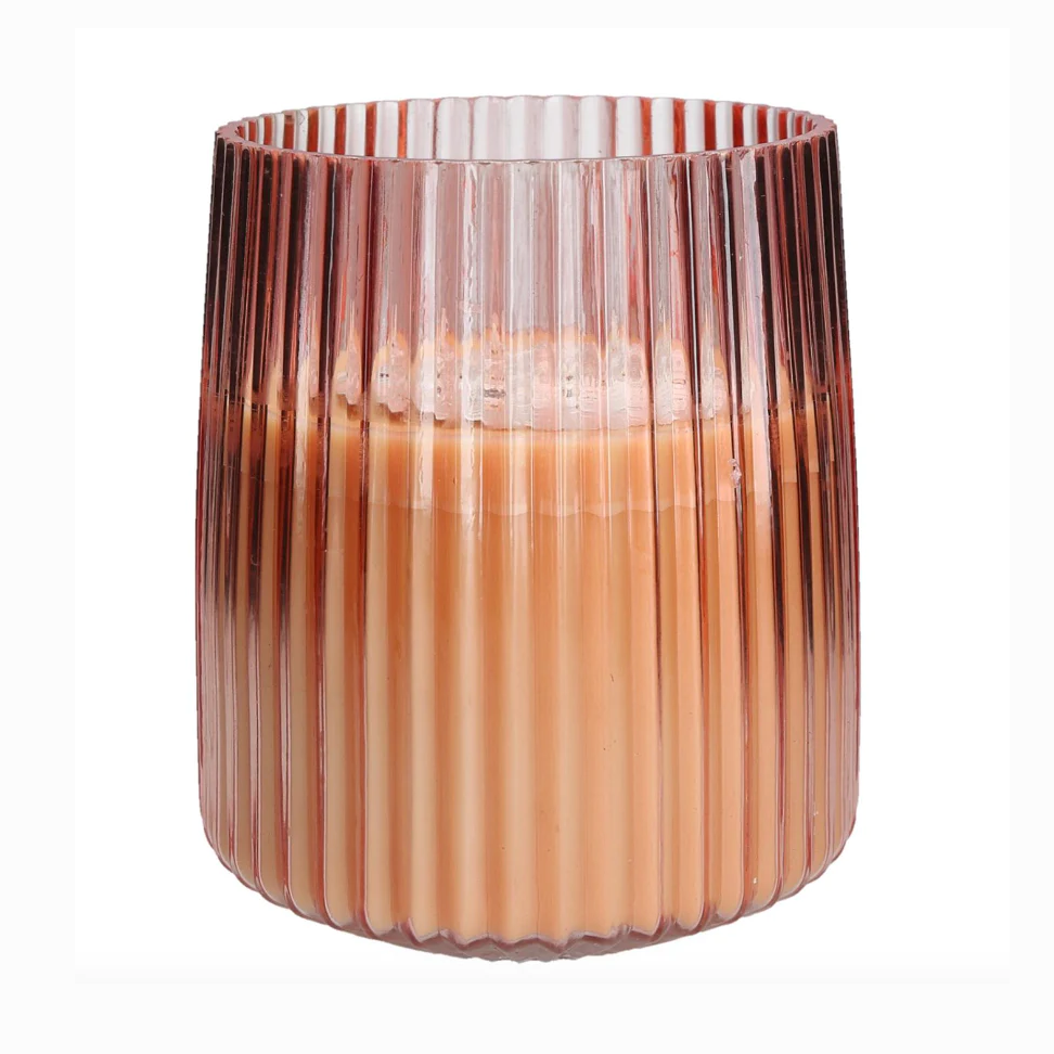 A large pink glass candle with a proprietary soy-blend wax, designed with vertical ridges and a warm light hue.