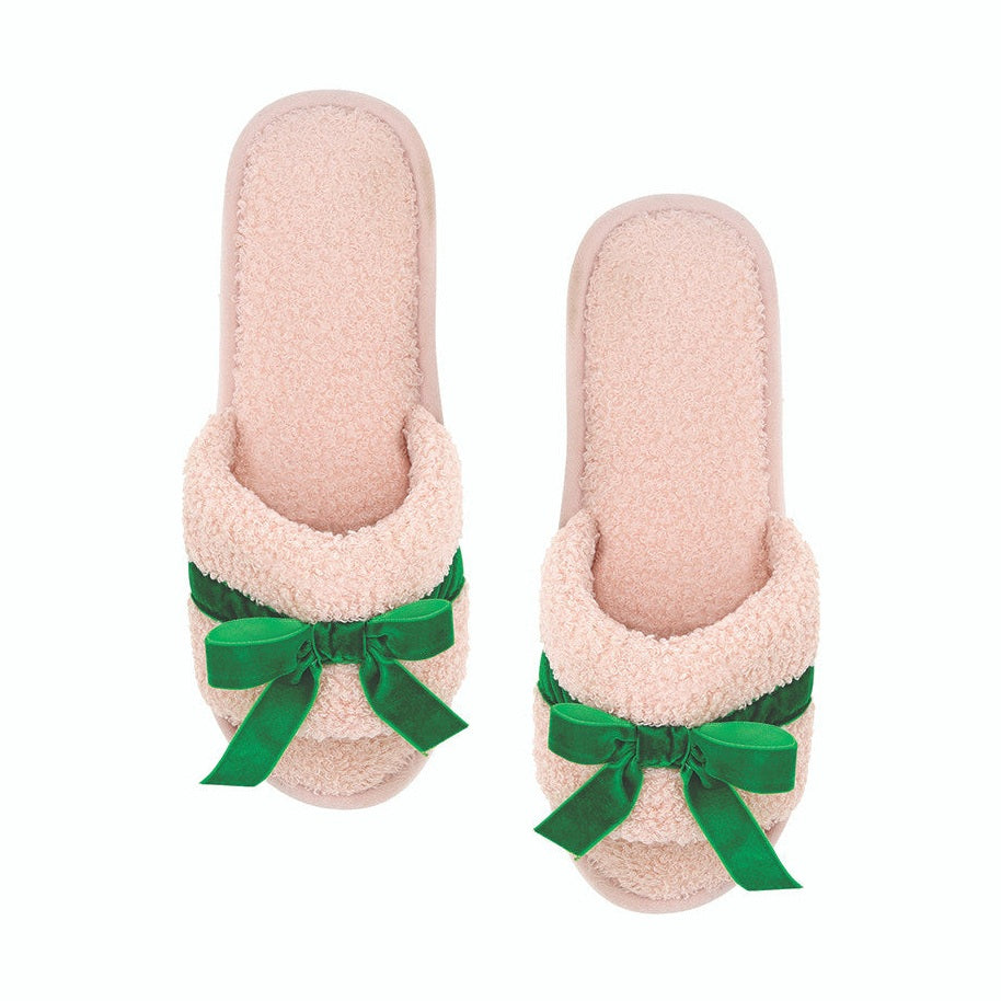 Pair of pink slippers with green bows on a white background