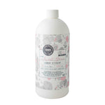 Commercial product photography of Bridgewater Candle Company Sweet Grass Laundry Detergent, featuring a white bottle on a white background with a gray and pink marbleized label and a circular bridge-themed brand logo