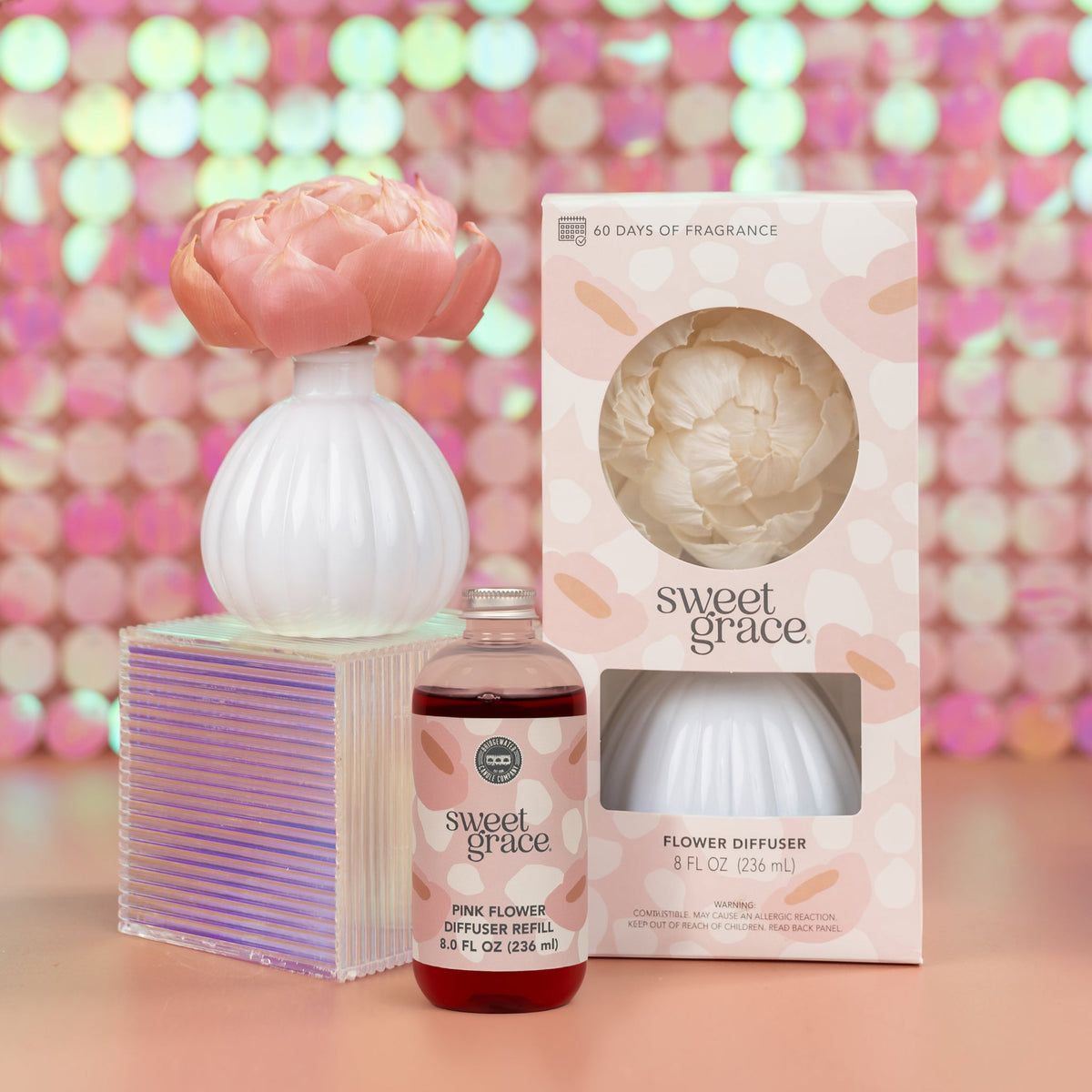 Flower diffuser with an oil refill and its box on a sequin background