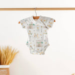 Baby onesie with dogs eating beignets print hanging on a wooden hanger against a white background.