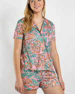 Woman wearing pink floral print short sleeve pajama set with orange piping