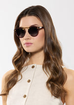 Woman in a cream top wearing espresso round sunglasses