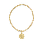 Gold beaded stretch bracelet with a round Saint Benedict medal charm