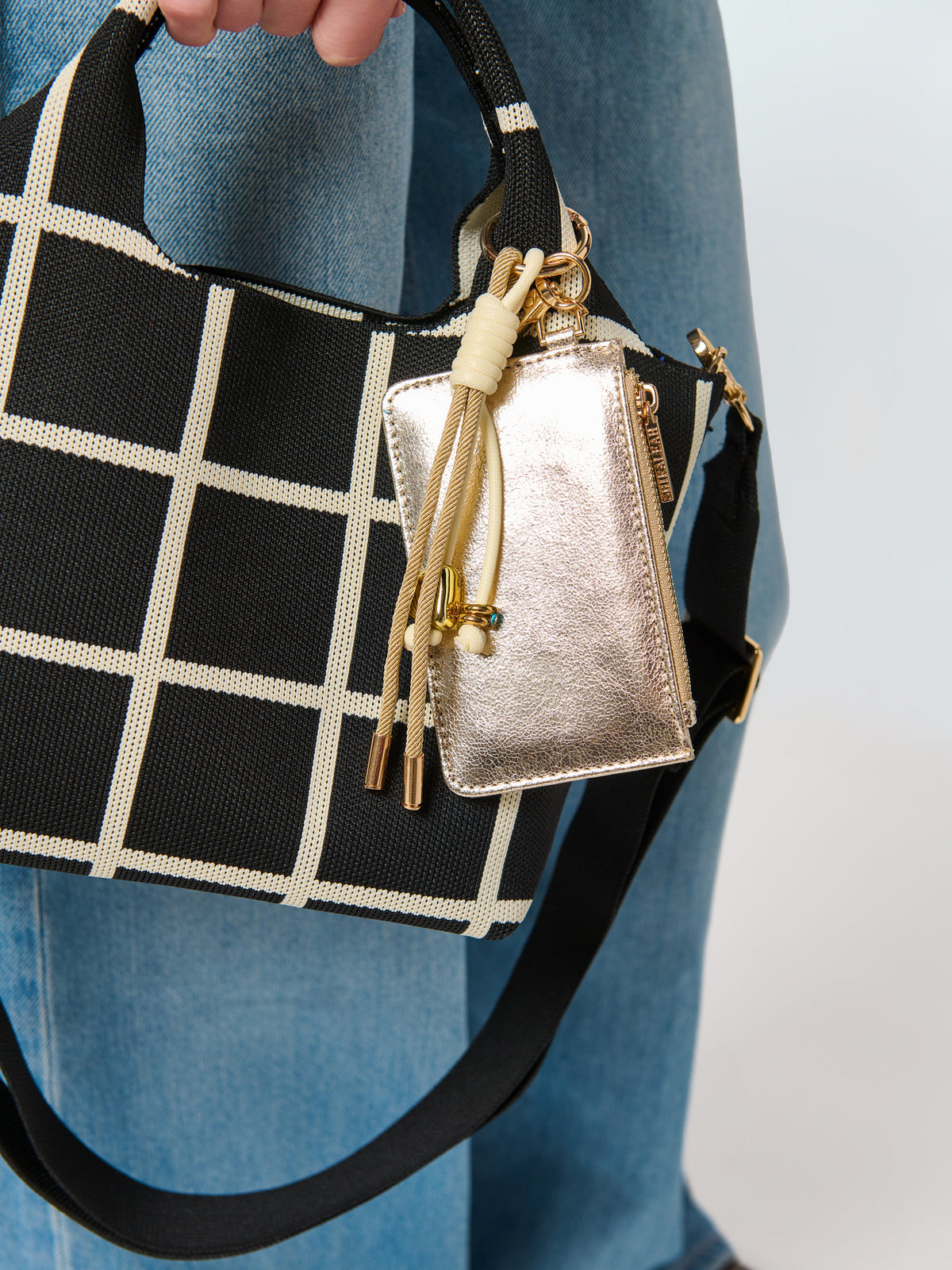 Gold card case charm clipped to a black and cream check tote
