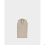 Pebble-grain leather accessory by an unknown designer featuring a taupe finish, visible tonal perimeter stitching, and a small gold-tone metallic logo emblem at the bottom corner against a neutral studio background