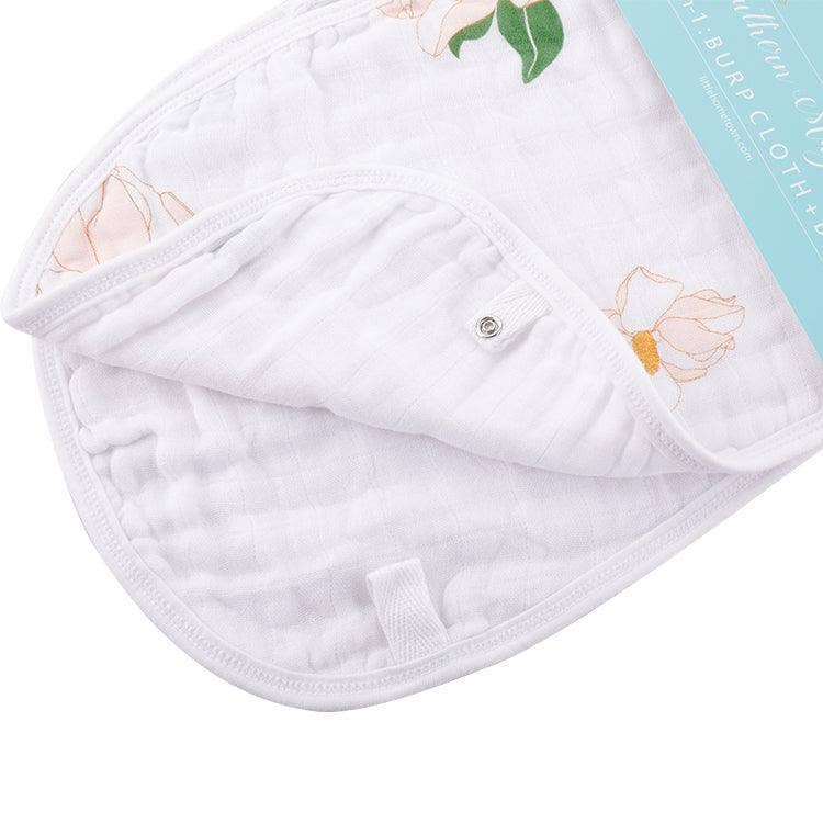 Magnolia print burp cloth folded to show its snap and plain white back