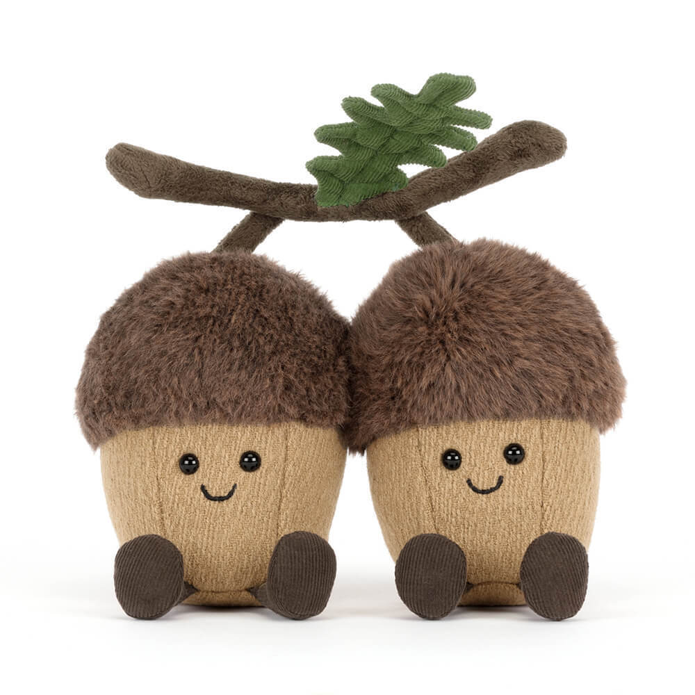 Two plush acorn toys with faces and a twig on a white background