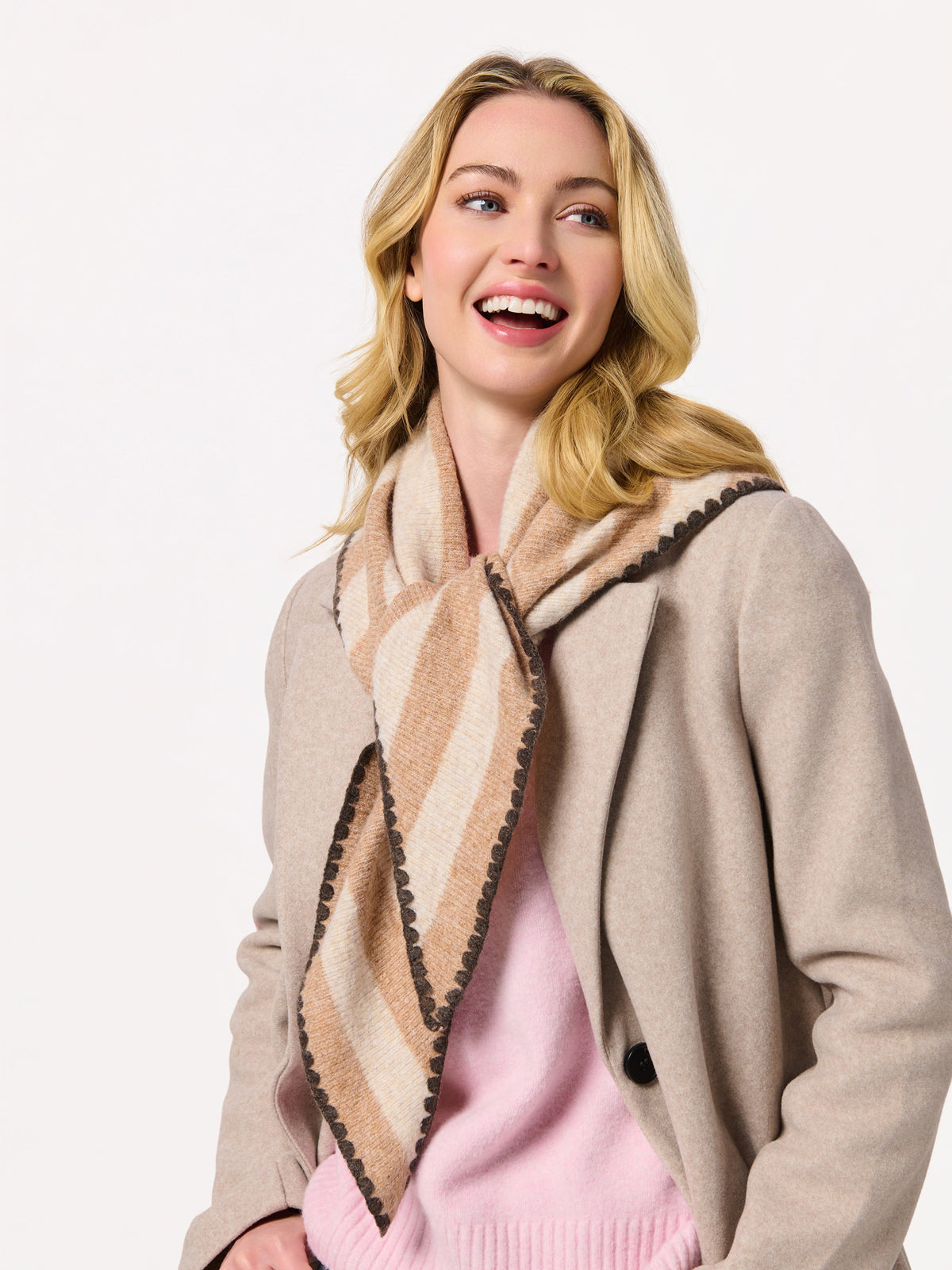 Smiling woman wearing an oatmeal striped scarf with a camel coat