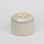 Iridescent candle holder with a candle on a light gray background