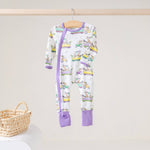 White zip footie with lavender trim and a print of zoo animals riding colorful parade floats