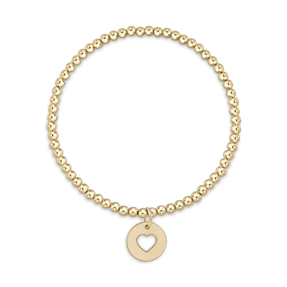 Gold beaded stretch bracelet with a round charm featuring a cutout heart