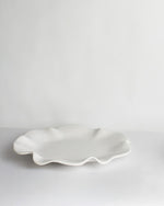 White ceramic dish with wavy edge on a light gray background