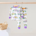 White two-piece pajama set with lavender cuffs and a print of zoo animals riding colorful parade floats