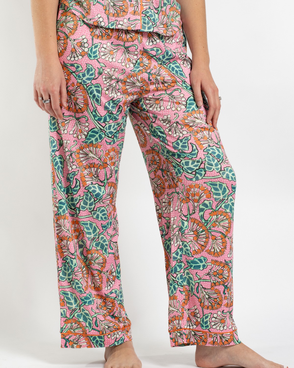 Person wearing pink floral print pajama pants with orange trim