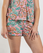 Person wearing pink floral print pajama shorts and matching button down shirt with orange piping
