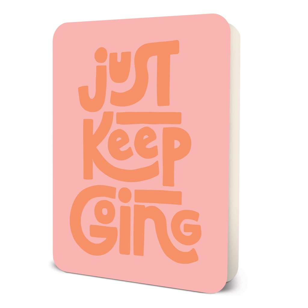 Pink notebook with orange text reading Just Keep Going