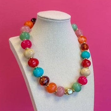 Multicolor statement bead necklace with a gold center bead on a display bust