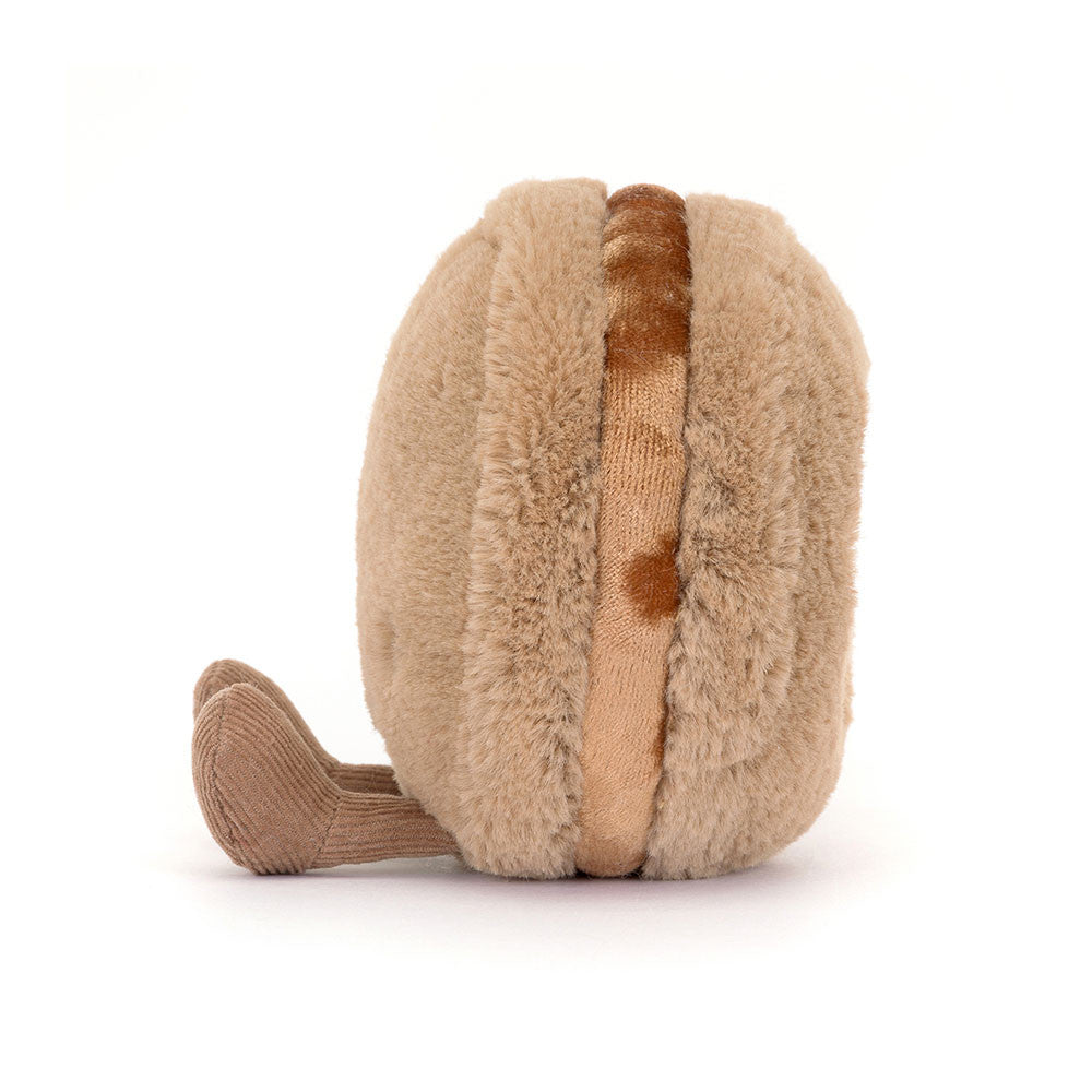Side view of a tan plush macaron showing its brown filling and corduroy feet
