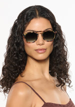 Woman with curly hair wearing tortoiseshell double-bridge sunglasses