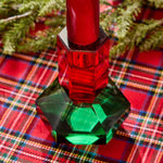 Green crystal candleholder with a red taper on a plaid tablecloth
